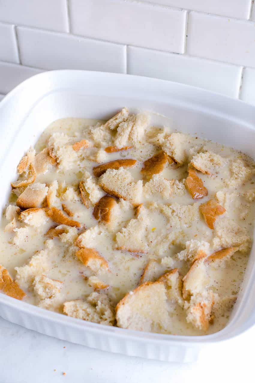 Bread cubes soaking pudding mixture in baking dish 