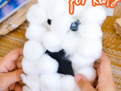 Ghost cotton ball craft on table with kids hands