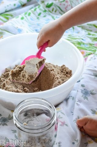 Toddler hand shoveling sand
