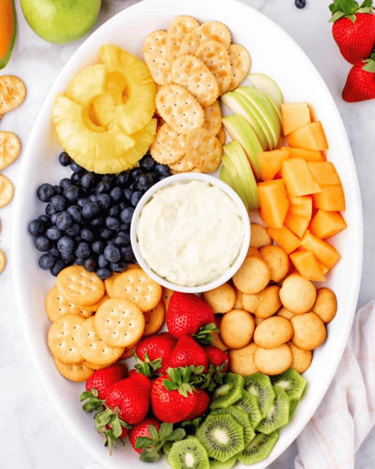 fruits on a platter with dip and cookies