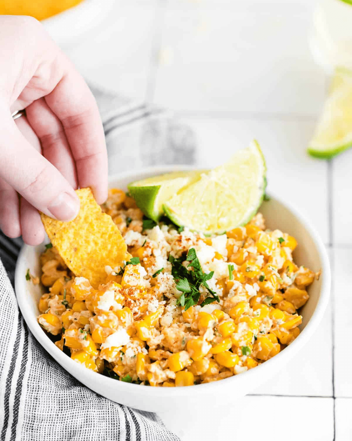 Mexican street corn dip in a white bowl with lime