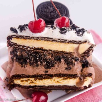 Ice cream sandwich cake on white plate, with cherries on top.
