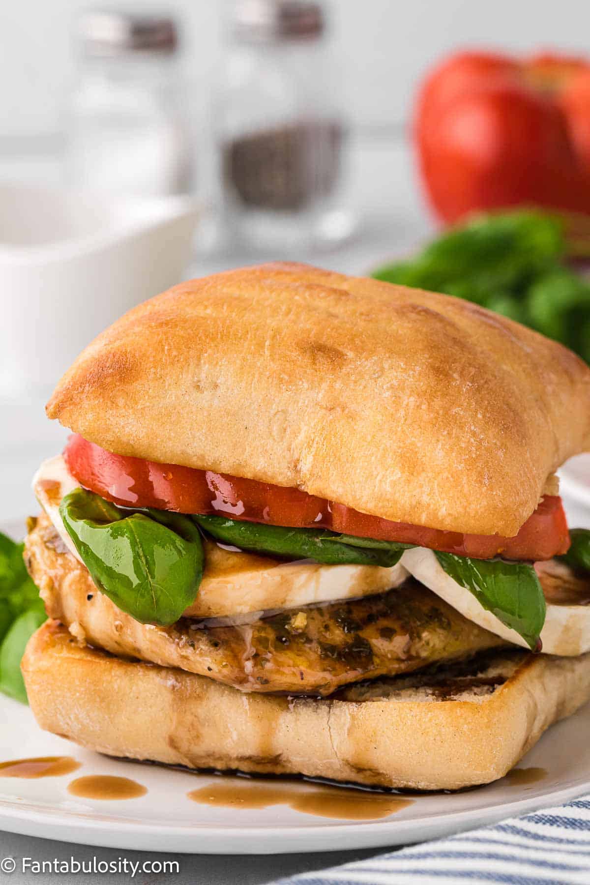 Chicken Caprese Sandwich on white plate, with balsamic dripping on to plate.