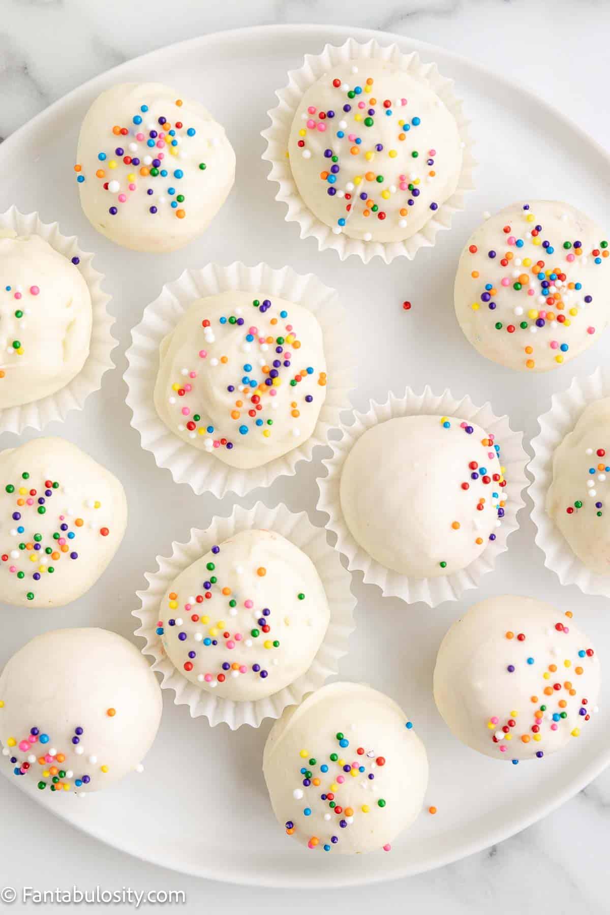 Sugar cookie truffles with sprinkles, on white plate.