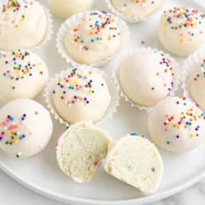 Sugar cookie truffles on white plate, with seeing the inside of one.