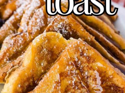 Slices of French toast on platter with syrup and blueberries.