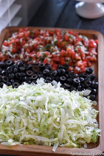 Brown tray full of lettuce, black olives, pico