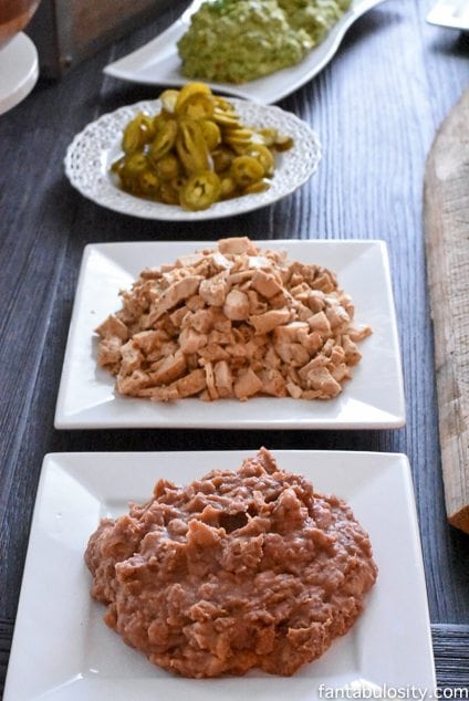 Refried beans, chicken and jalapenos on white plates