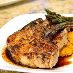 Grilled pork chop on plate next to asparagus.