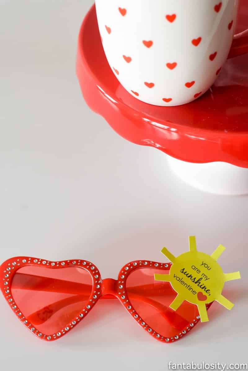 Red heart-shaped sunglasses on table with yellow sun cut-out