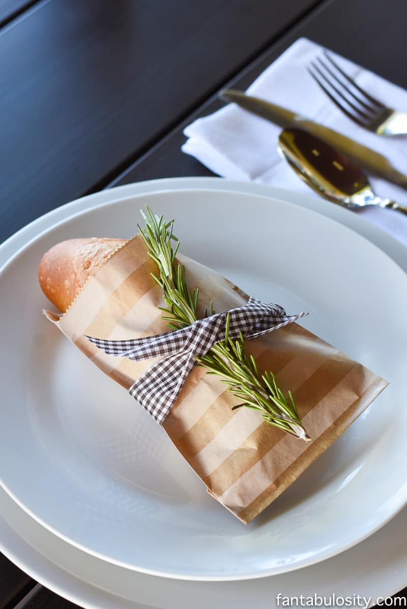 Place setting idea for dinner party: rosemary, favor bag, ribbon, bread
