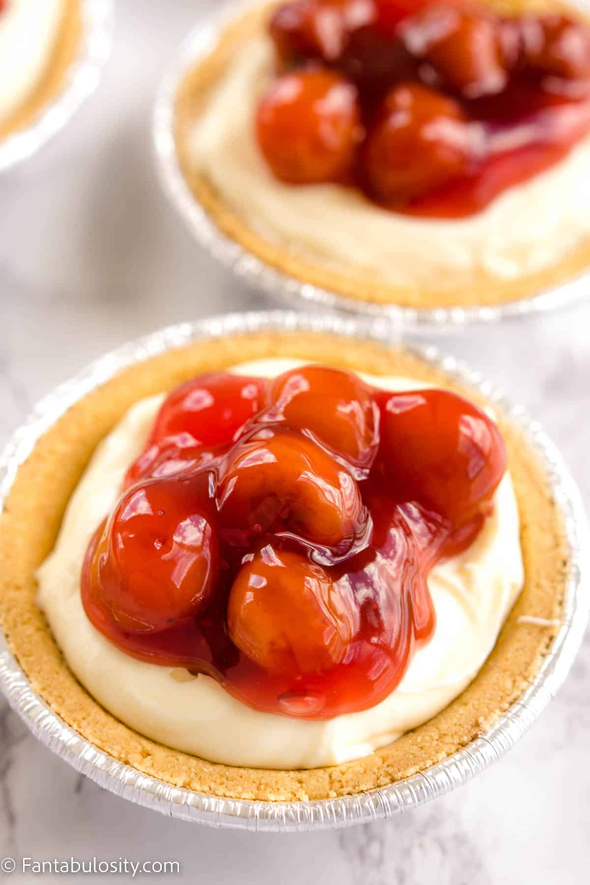 No Bake Mini Cheesecakes on counter, with cherry pie filling on top.