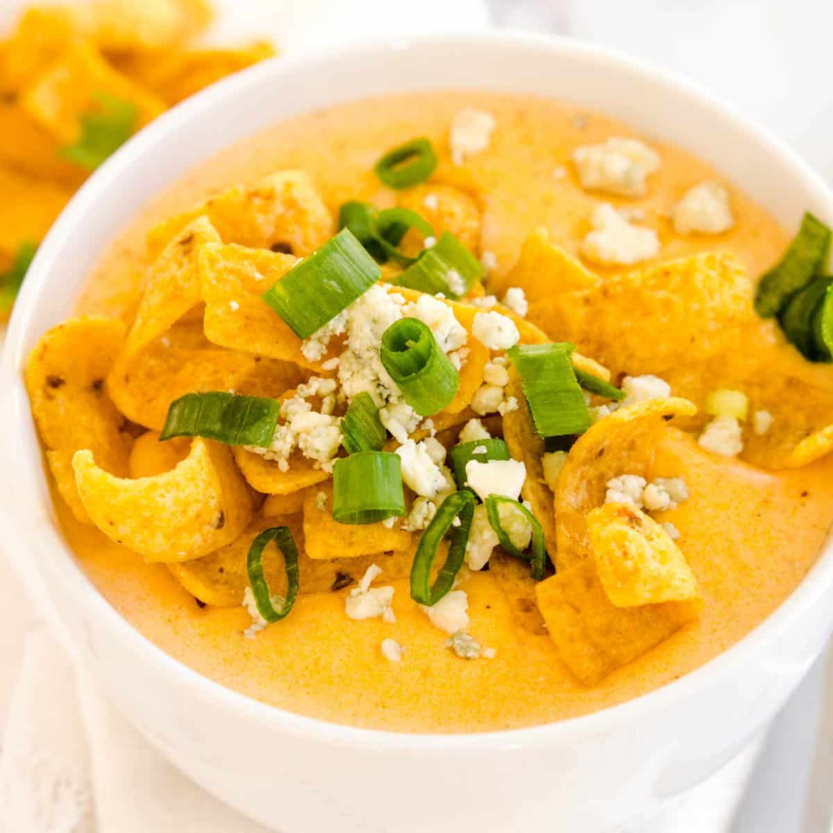 Bowl of buffalo chicken soup with green onions and chips.