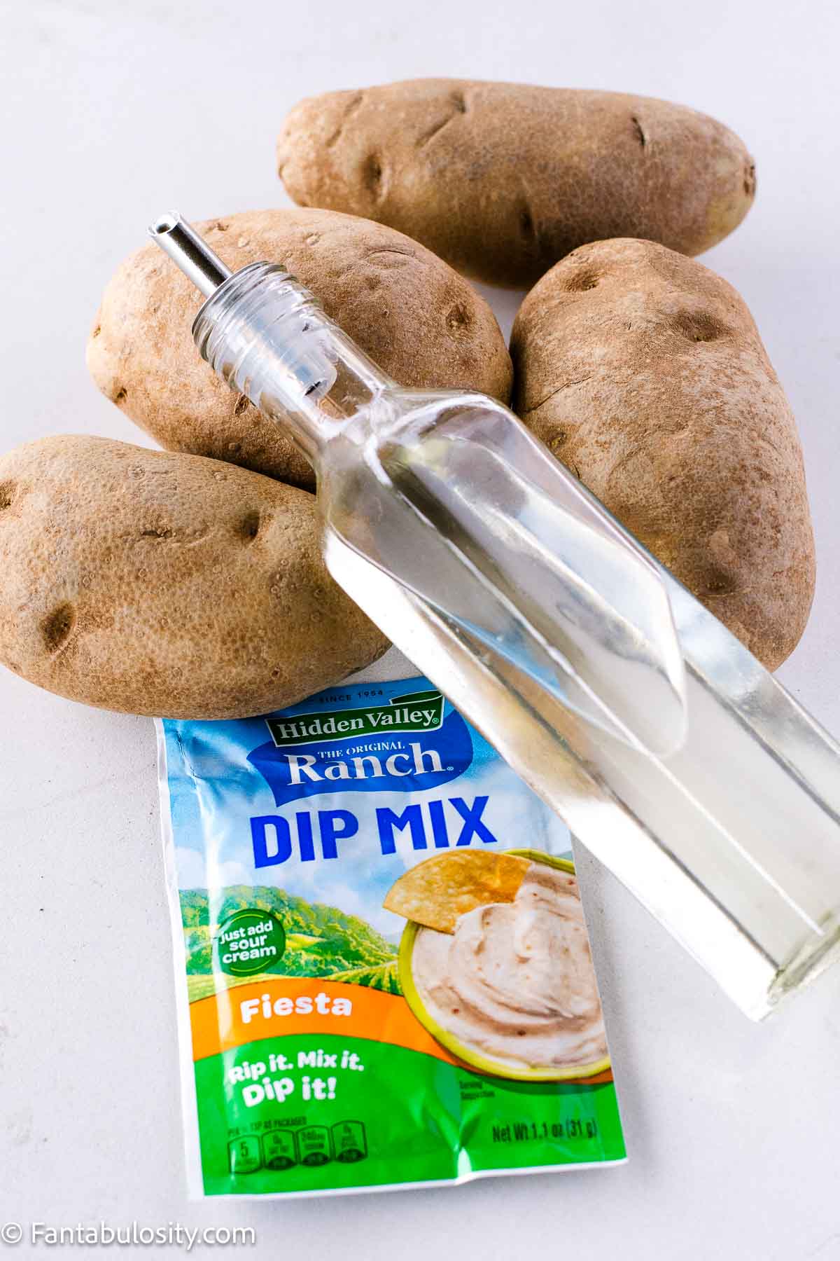 Oil, potatoes and Fiesta ranch dressing seasoning on table.