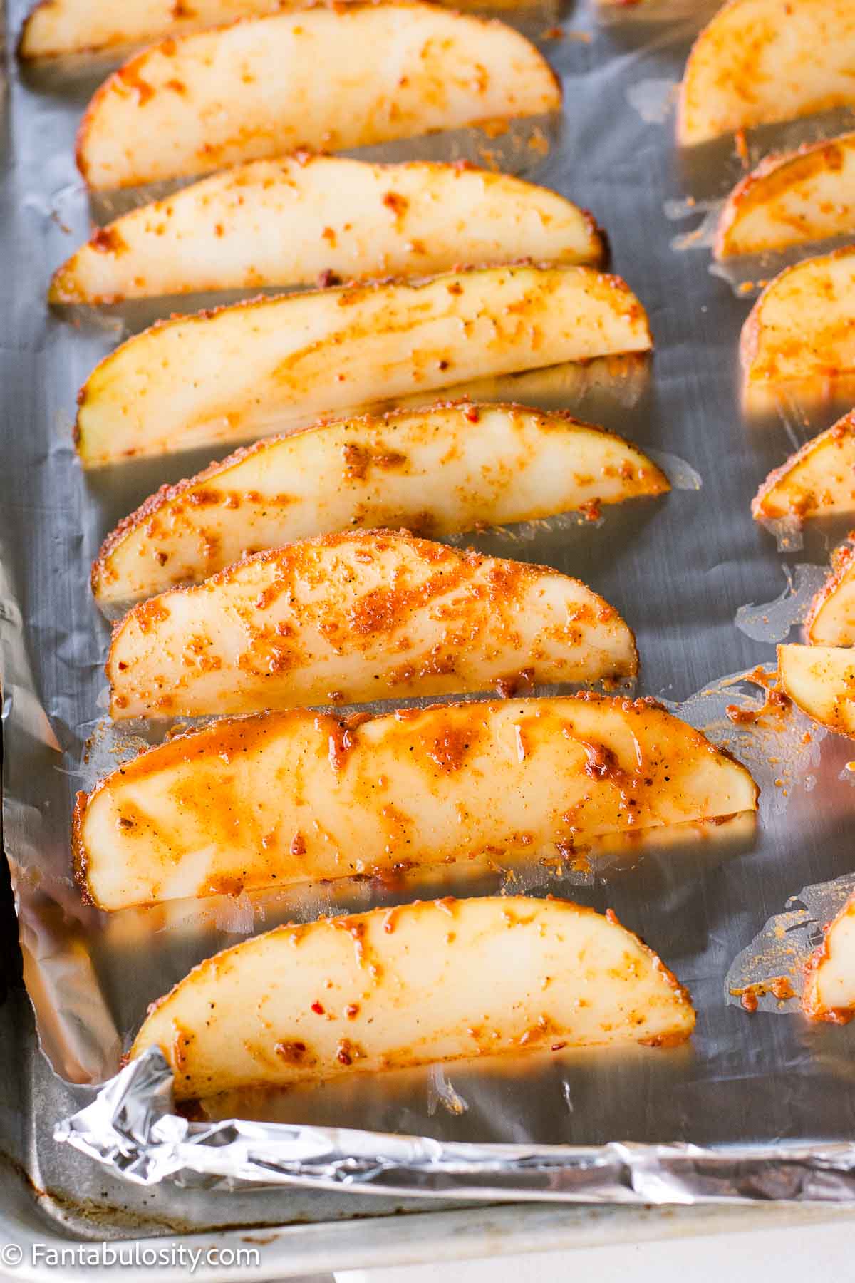 Seasoned potato wedges on baking sheet.