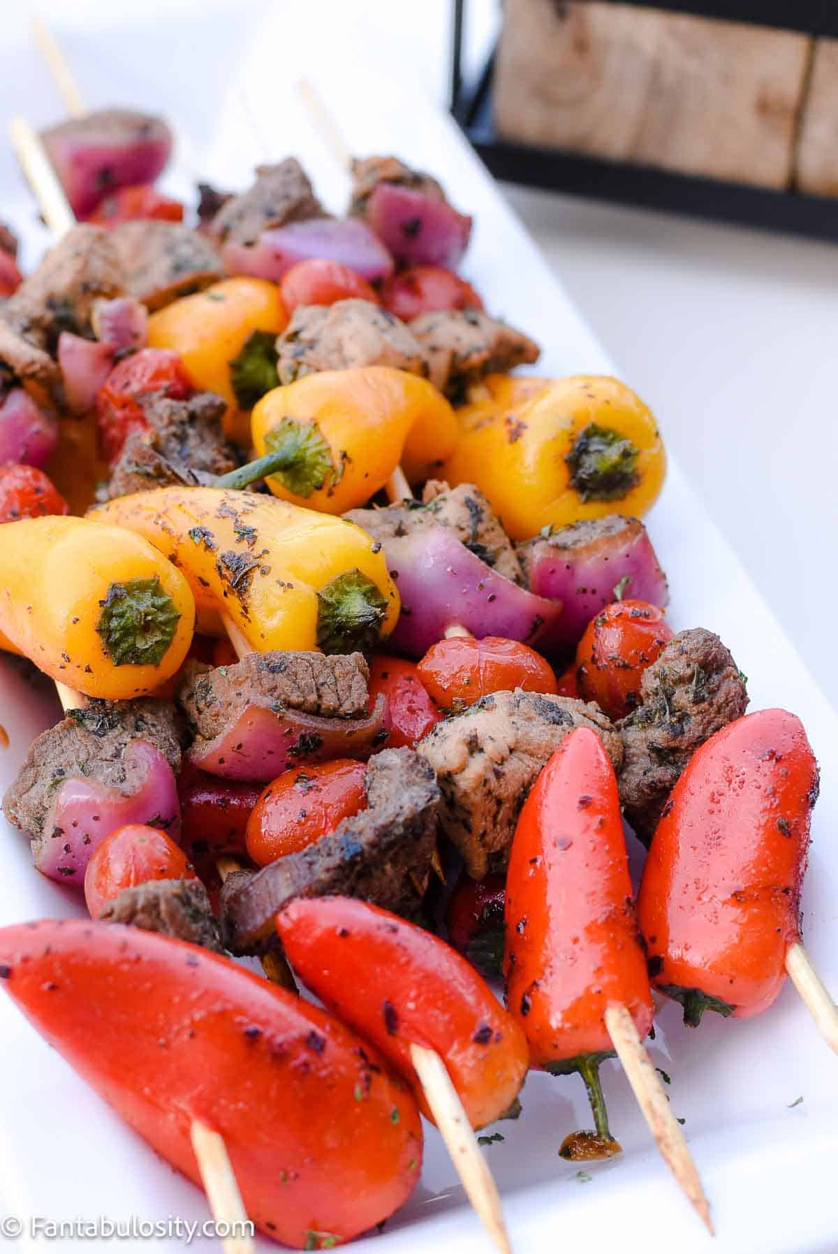 Kebobs for a backyard party, sitting on a white plate.
