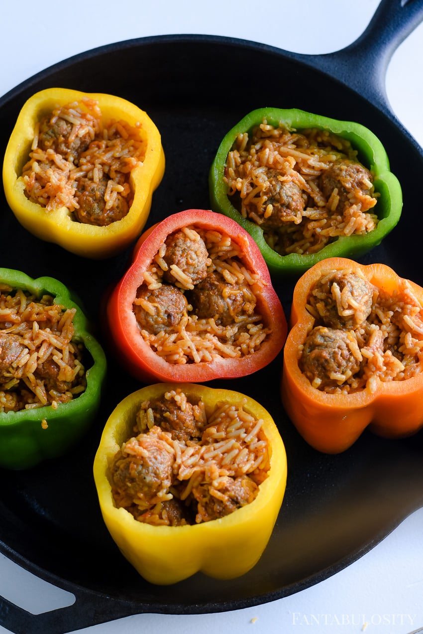 Stuffed peppers recipe, using bell peppers and baking in a cast iron pan. Cheese, rice and meatballs.