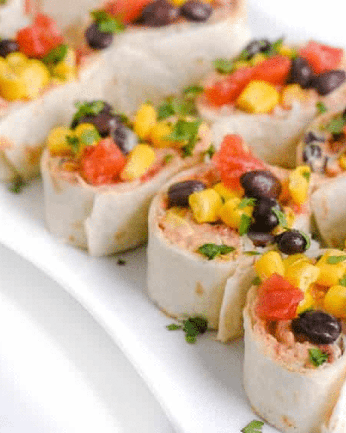 Taco pinwheels on a plate with black beans and corn
