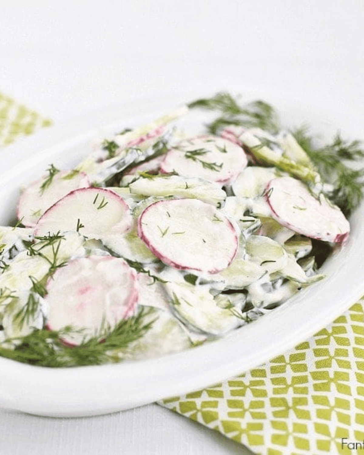creamy crunchy cucumber salad with dressing on a white plate