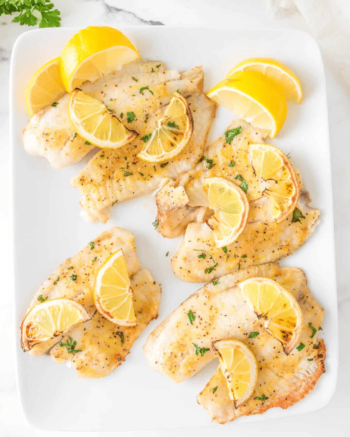Air Fryer Tilapia with lemons on a white plate