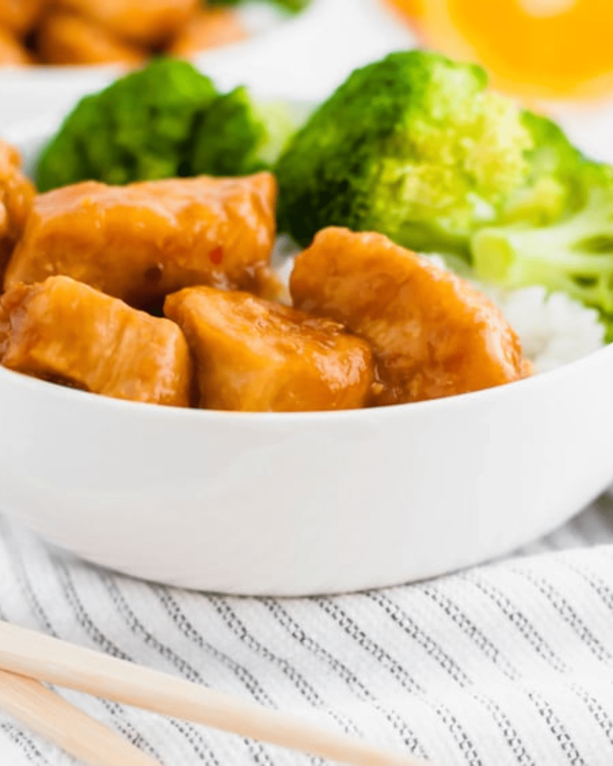 Instant pot orange chicken in a white bowl with broccoli and rice