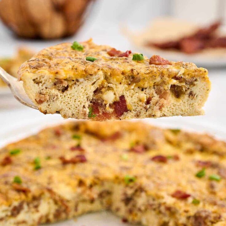 Slice of bacon and sausage quiche on spatula.