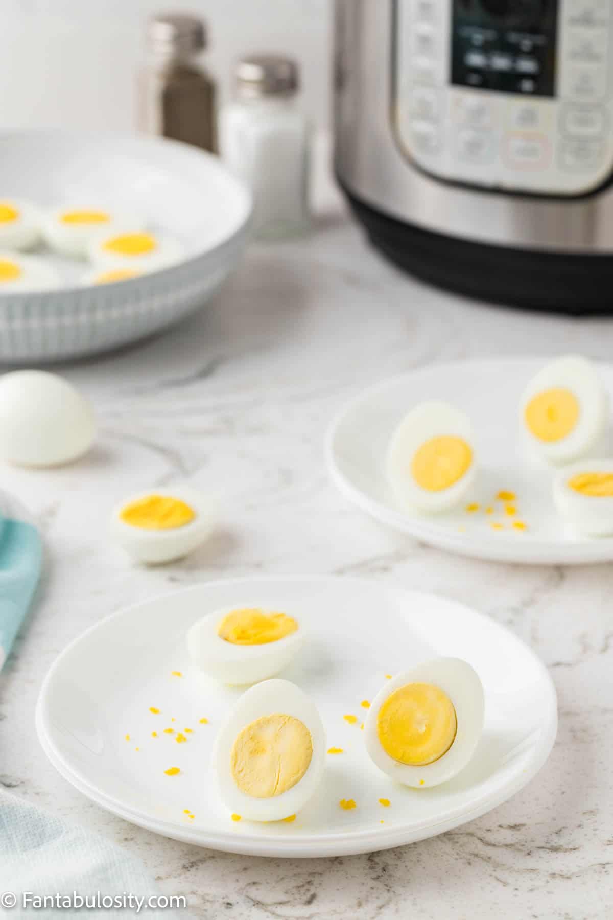 Sliced hard boiled eggs on plate next to Instant Pot