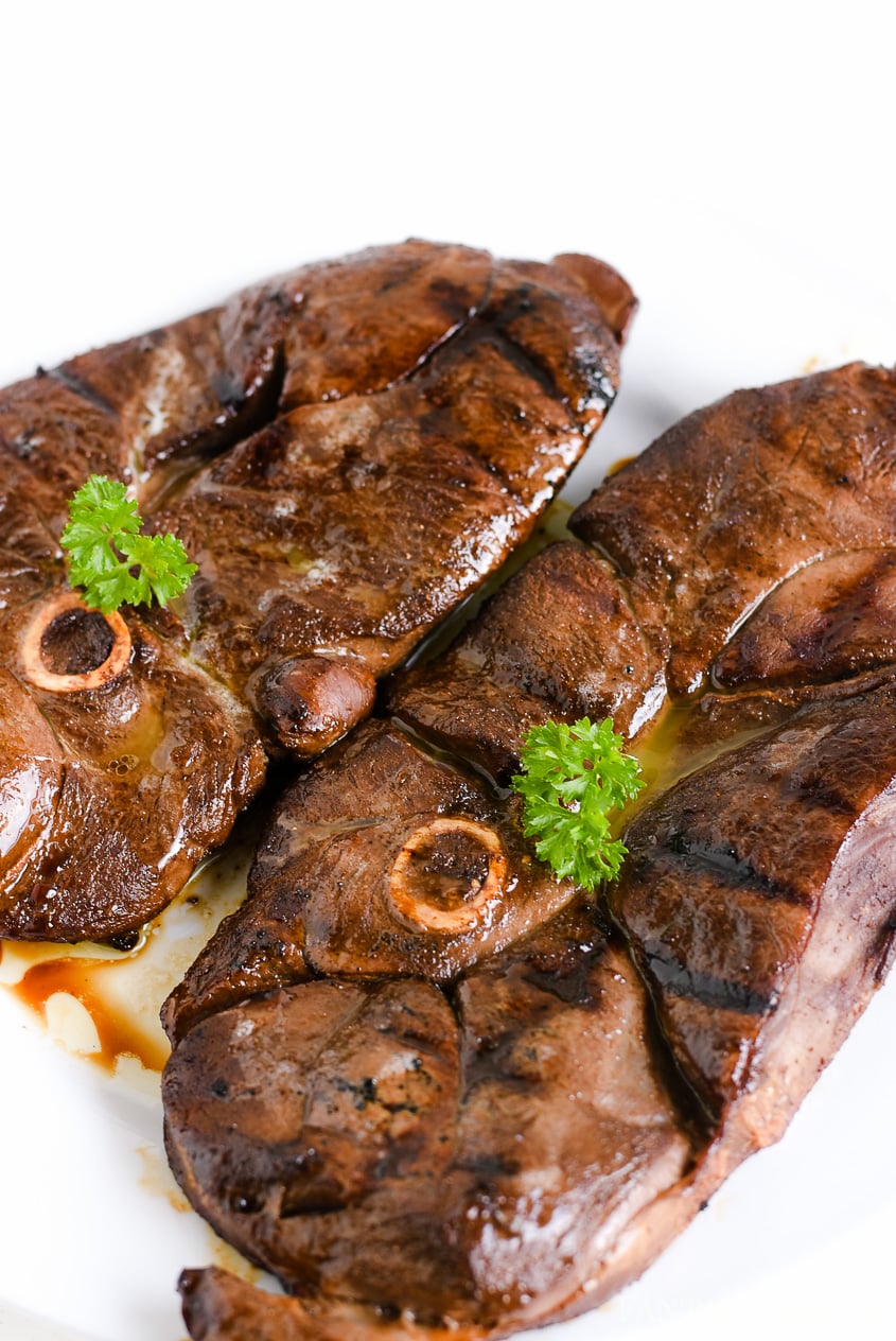 Grilled marinated deer steak on white plate. 