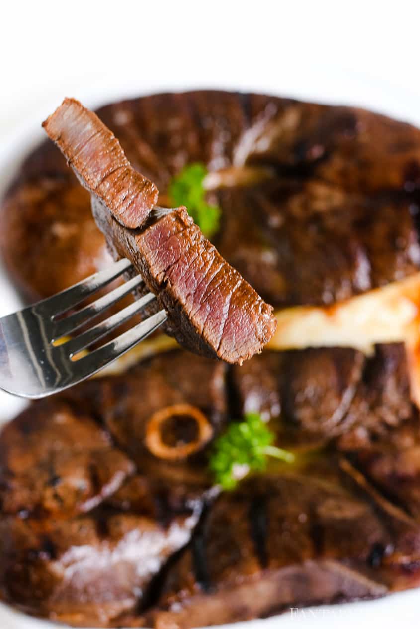 Bite of sliced marinated venison on fork. 