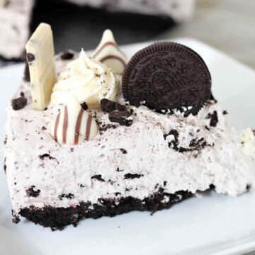 Slice of Oreo cheesecake with Oreo cookie and chocolate candy on top.