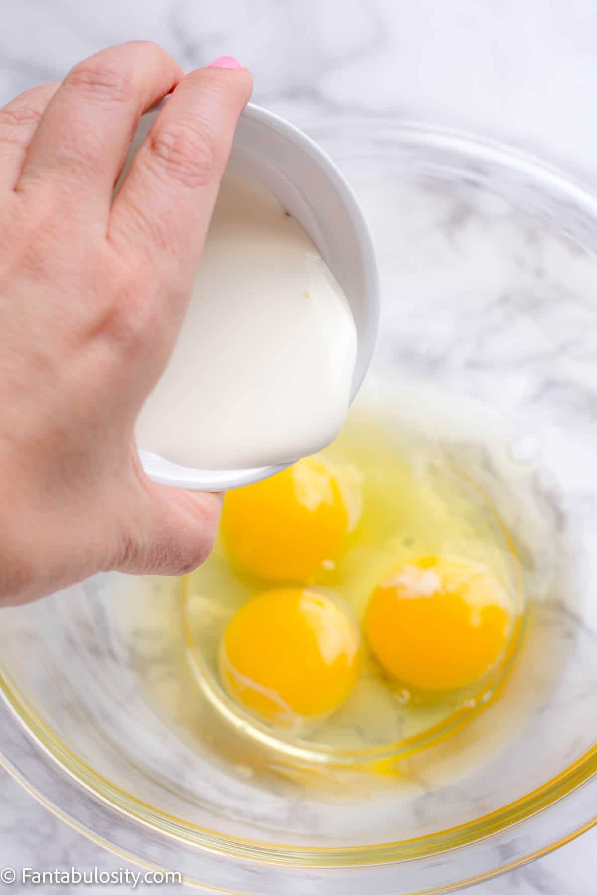 heavy cream pouring in bowl with eggs