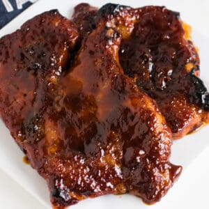 BBQ pork steaks cooked in the oven, that are on a white plate.