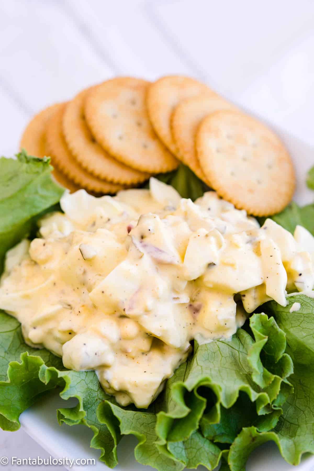 egg salad on bed of lettuce next to crackers