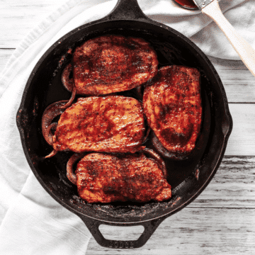 Boneless BBQ Pork chops sitting in cast iron skillet.