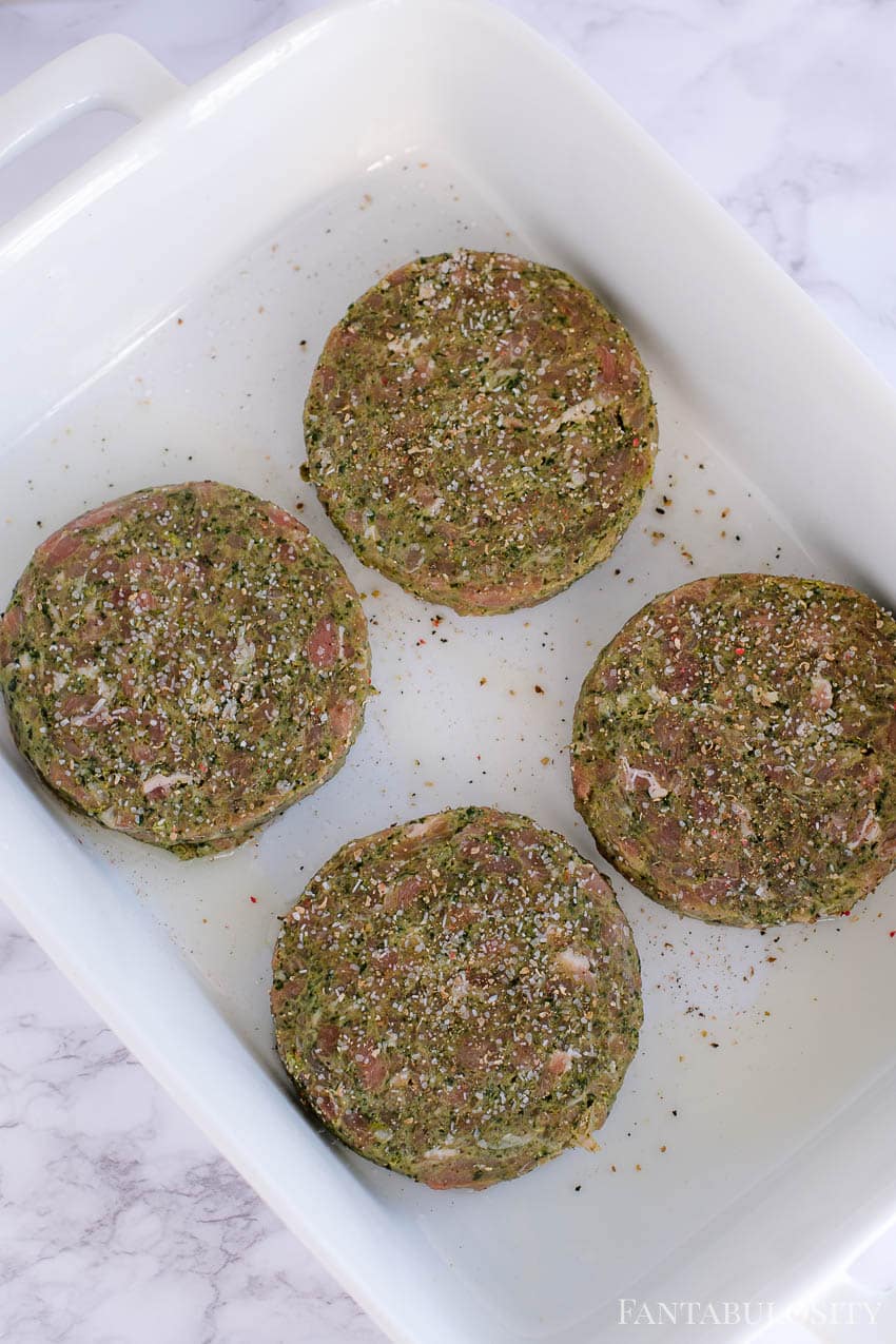 Turkey burgers in white baking dish, seasoned and ready for the oven