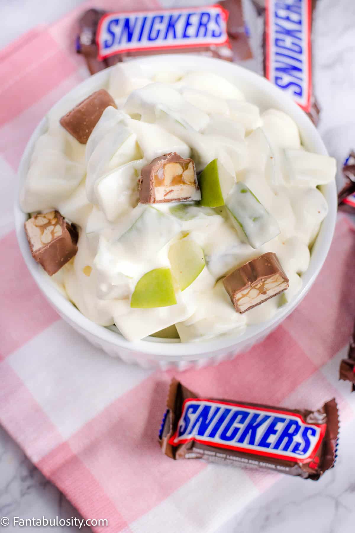 Apple Snicker Salad in bowl with fun size Snickers all around