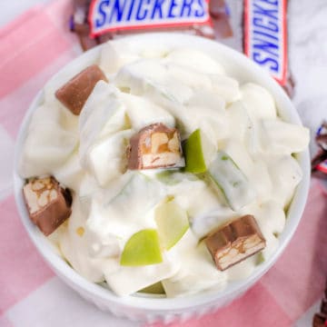 Apple Snicker Salad in white bowl with fun size Snickers around bowl