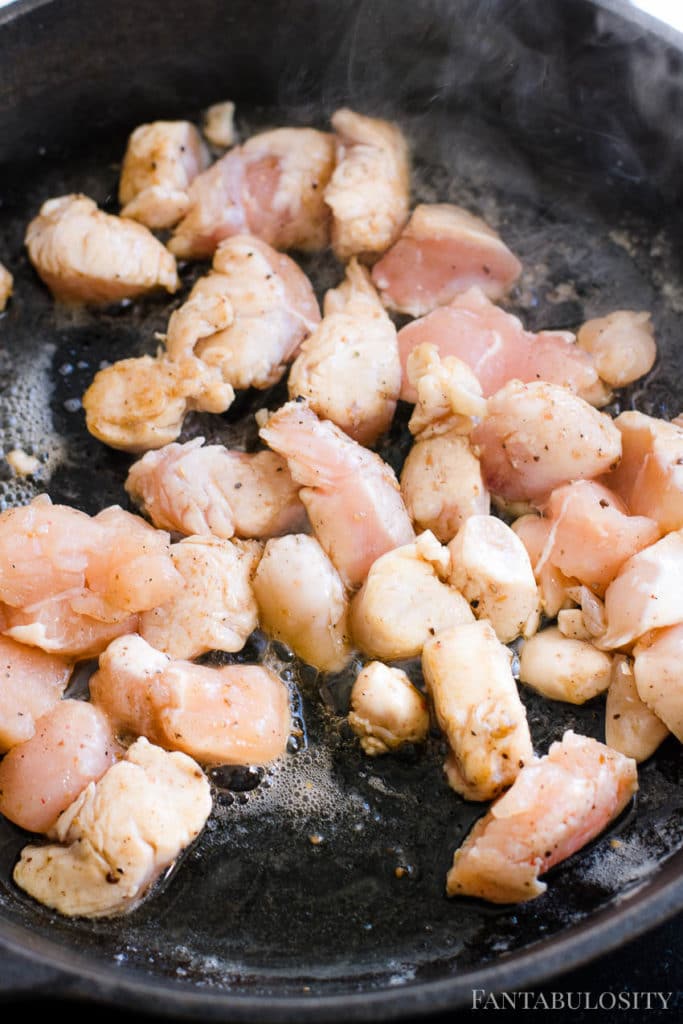 Chicken cooking in a cast iron skillet, in butter