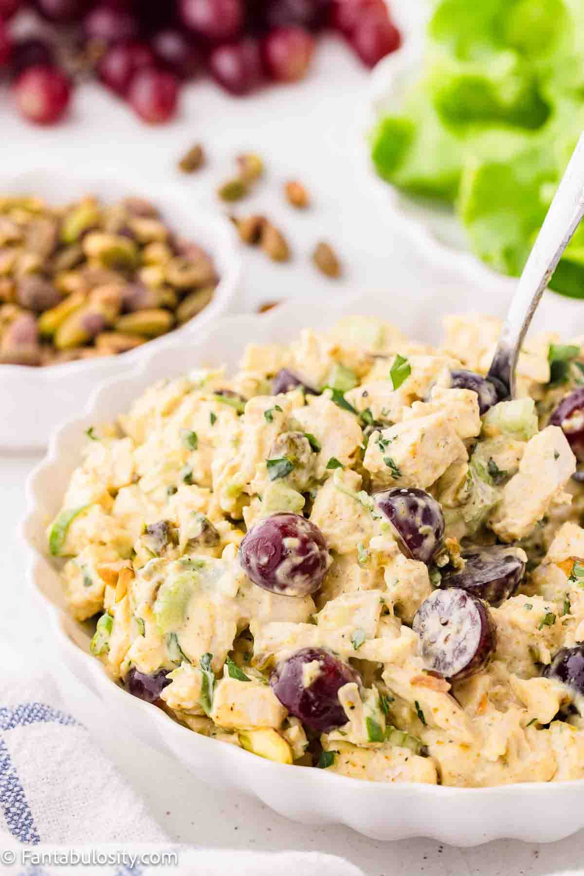 Curry chicken salad in bowl with spoon sticking out of it.