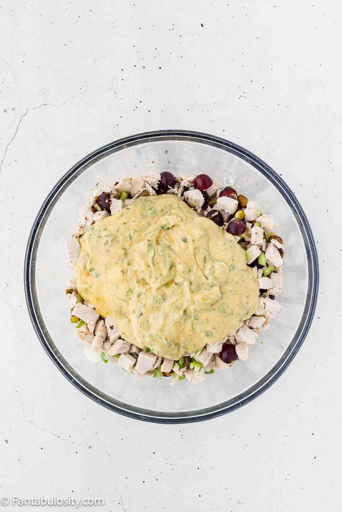 Dressing poured over chicken, grapes, parsley and celery in mixing bowl.