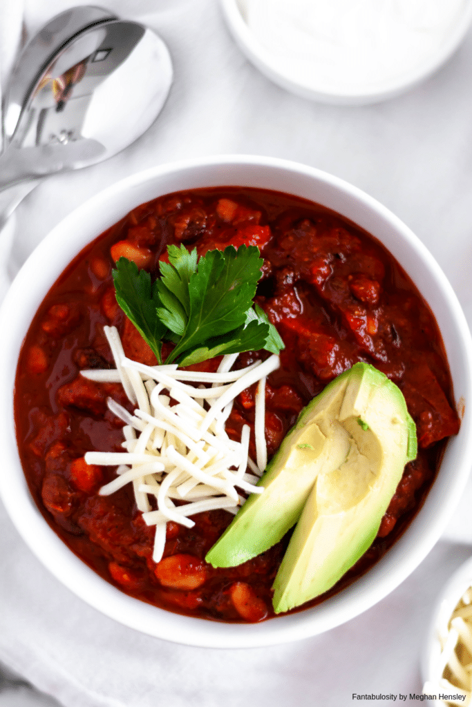 Vegetarian Chili in a white bowl with avocados on top