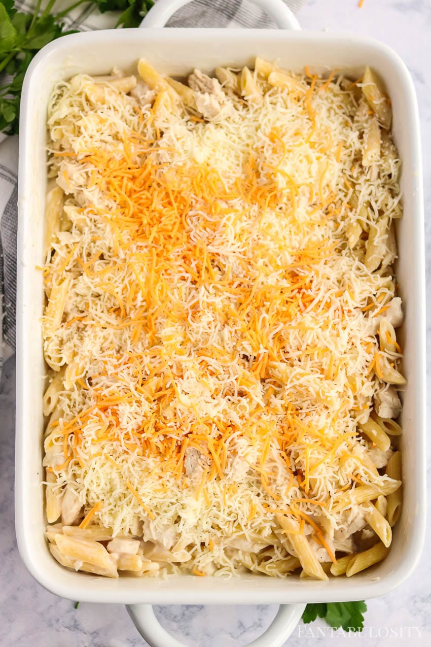Pasta in a baking dish with cheddar cheese