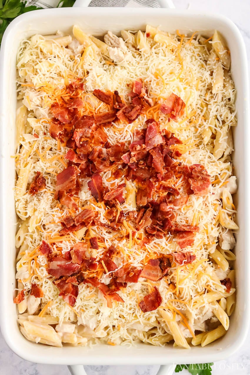 Sprinkled bacon on top of chicken bacon ranch pasta in baking dish