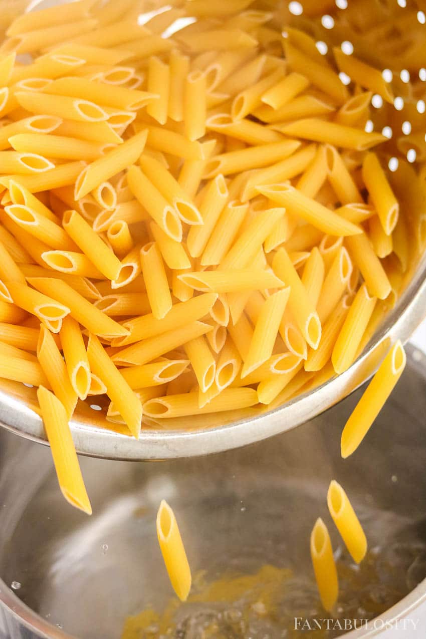 Pouring penne in to a stockpot to boil