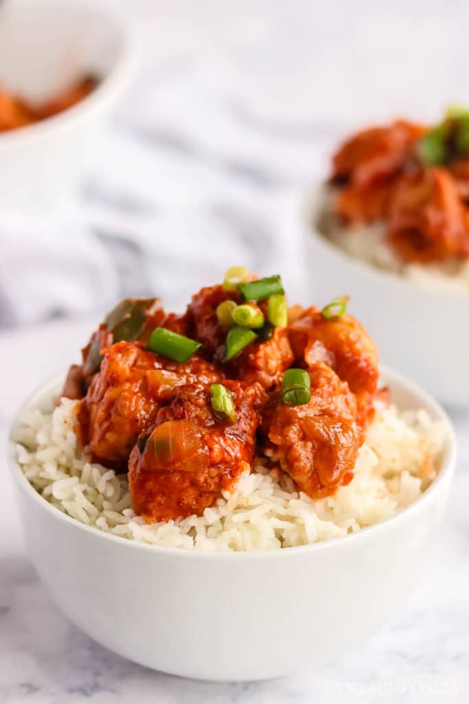 Chilli Chicken on top of rice in a white bowl