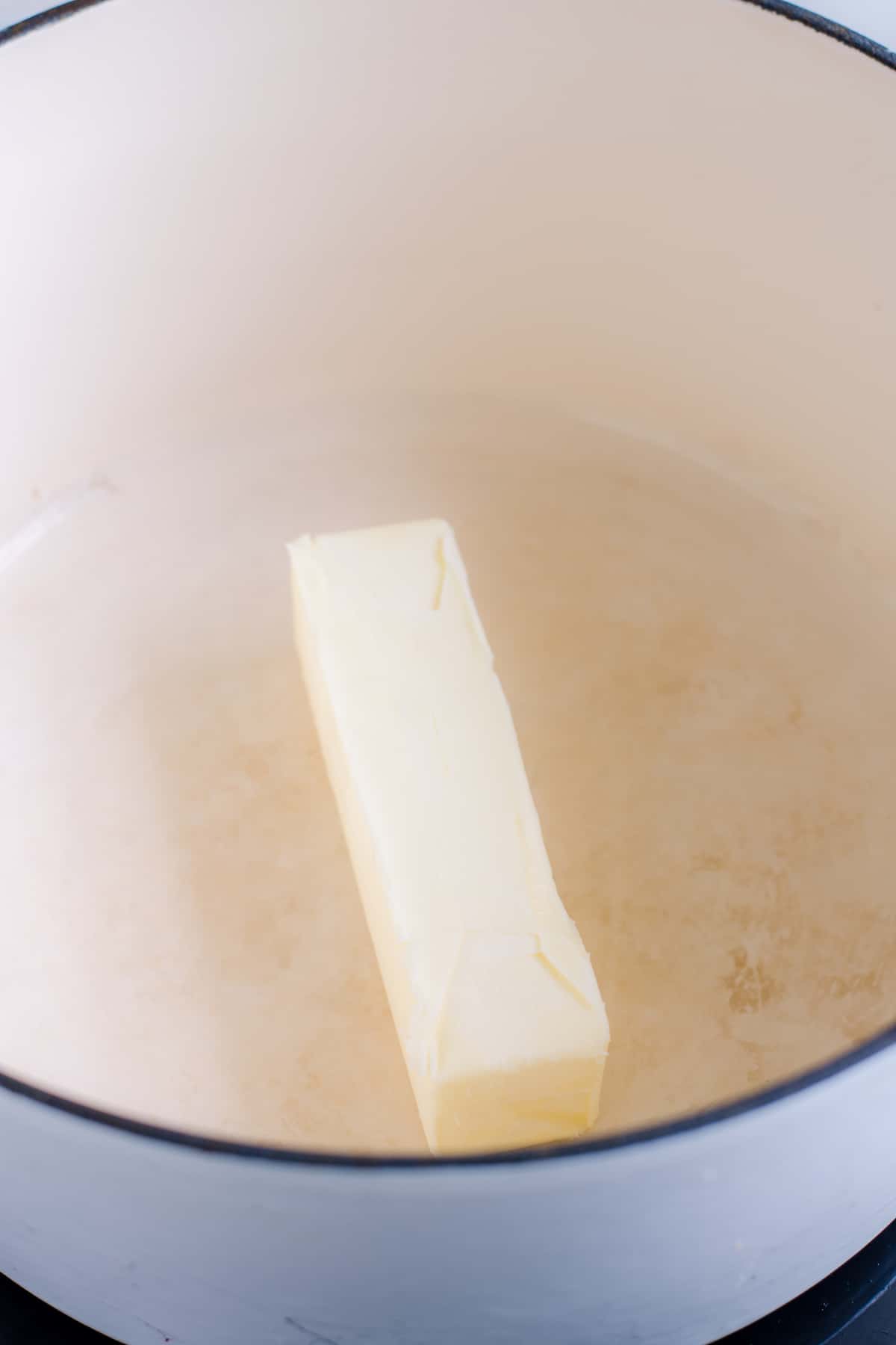 Stick of butter in white saucepan.