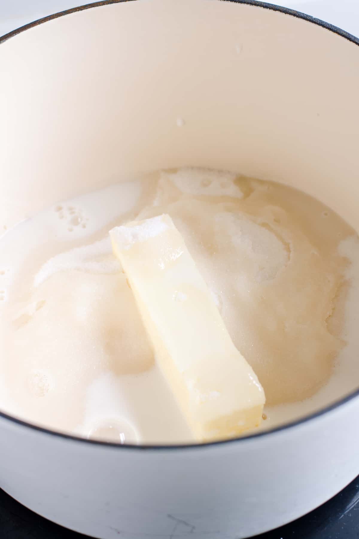 Milk added to sugar and butter in white saucepan