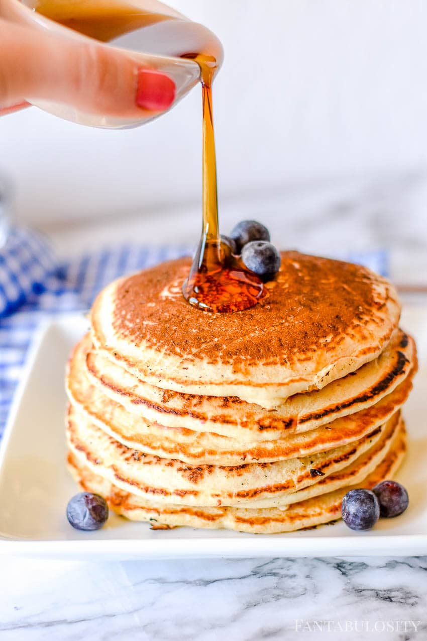 Pouring syrup on blueberry pancakes