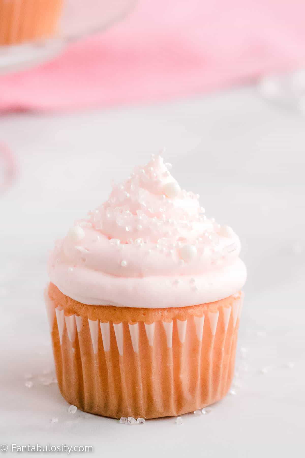 Pink champagne cupcake on marble counter.