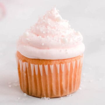 Pink champagne cupcake on white marble counter.